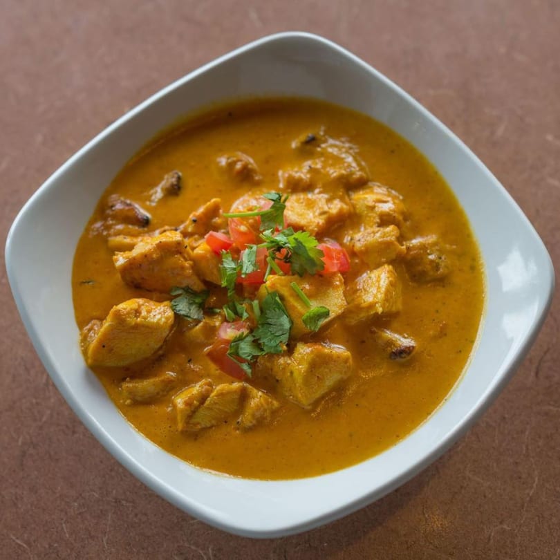 Gorkha Palace Indian Cuisine's chicken curry, garnished with fresh cilantro and diced tomatoes.